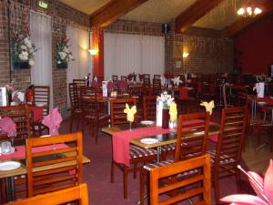 a dining room with tables and chairs with flowers on them at Corn Mill Lodge Hotel in Leeds