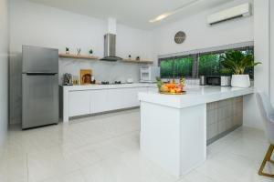 a white kitchen with a refrigerator and a counter at Villa Mimosa 1, Splendid 4 Bedroom Master Ensuite in Phuket Town