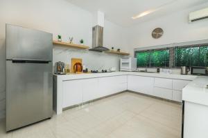 a kitchen with white cabinets and a stainless steel refrigerator at Villa Mimosa 1, Splendid 4 Bedroom Master Ensuite in Phuket Town