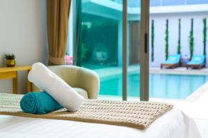 a hotel room with a bed with a towel and a chair at Villa Mimosa 1, Splendid 4 Bedroom Master Ensuite in Phuket Town