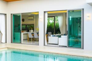 an image of a swimming pool in a house with sliding glass doors at Villa Mimosa 1, Splendid 4 Bedroom Master Ensuite in Phuket Town