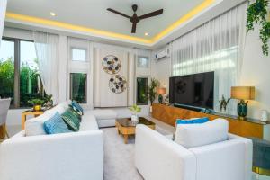 a living room with white furniture and a flat screen tv at Villa Mimosa 1, Splendid 4 Bedroom Master Ensuite in Phuket Town