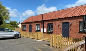 un bâtiment en briques avec une voiture garée devant dans l'établissement Bay Cottages, à North Somercotes