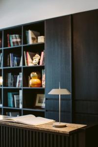 a desk with a lamp in front of a book shelf at Hotel Piccola Vela in Desenzano del Garda
