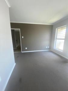 an empty living room with a window and a white wall at Ore Private property in Midrand