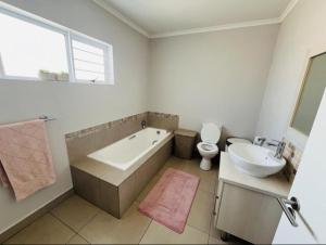 a bathroom with a tub and a toilet and a sink at Ore Private property in Midrand +10 photos