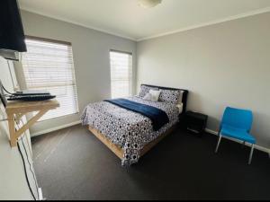 a bedroom with a bed and a blue chair at Ore Private property in Midrand