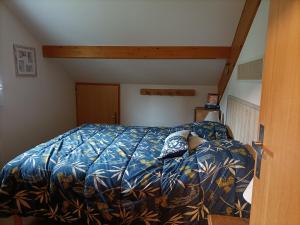 una camera da letto con un letto con un piumone blu di Appartement GERARDMER - Magnifique vue sur le lac - jusqu'à 4 personnes a Gérardmer