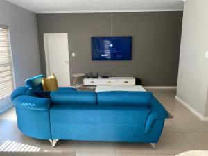 a blue couch in a living room with a tv at Ore Private property in Midrand