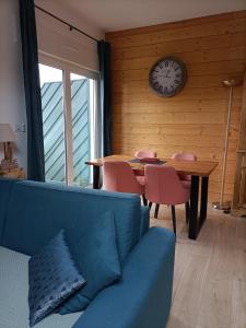 un soggiorno con divano, tavolo e orologio. di Appartement GERARDMER - Magnifique vue sur le lac - jusqu'à 4 personnes a Gérardmer