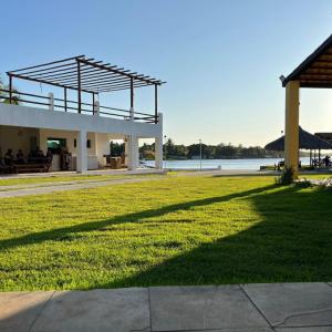 a building with a grassy field next to a body of water at Pousada Paraíso do Banana - Lagoa do Banana in Caucaia
