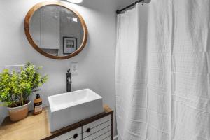 a bathroom with a white sink and a mirror at Charming Ivy Street House With Porch Swing in Mooringsport +24 photos