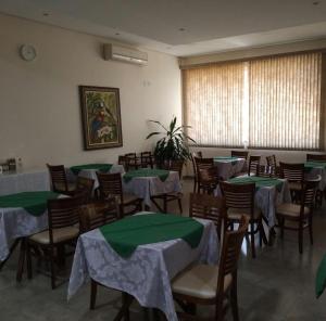 a room with tables and chairs with green table cloth at Palmares Hotel in Guaíra
