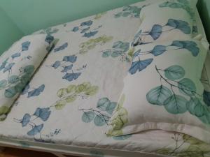 a bed with a blanket with blue flowers on it at Thuy An Homestay in Xuan An