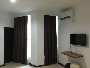a room with a tv and a window with curtains at Permai Hotel in Sibu