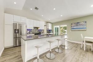 a kitchen with white cabinets and bar stools at 2 Mi to Deerfield Beach Home with Outdoor Oasis! in Deerfield Beach