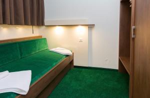 a small room with a green bed and green carpet at Residence Caddies Club in Crans-Montana