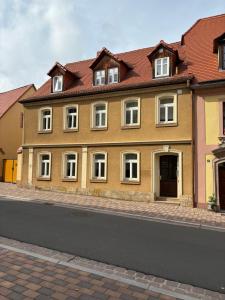 a yellow building with white windows on a street at Ferienwohnung H&M Immobilien Querfurt 2 in Querfurt