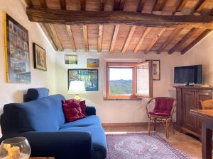 a living room with a blue couch and a tv at La Pergola tra Siena e Chianti in Badesse