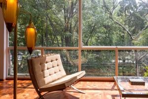 a living room with a chair and a large window at Deco House with Park View Rooftop in Mexico City
