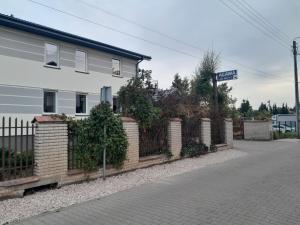 a fence in front of a white building with a street sign at Pokoje Gościnne Agawa in Łomianki