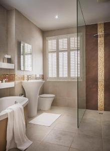 a bathroom with a tub and a toilet and a sink at The Regency By Birch Stays in Chester