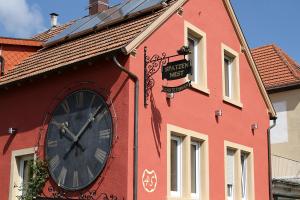 a large clock on the side of a red building at Gästehaus Spatzennest in Maikammer