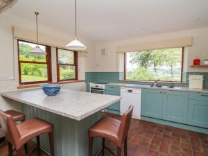 a kitchen with blue cabinets and a counter with stools at Oak Apple Cottage in Presteigne +32 photos