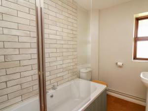a white bathroom with a tub and a sink at Oak Apple Cottage in Presteigne