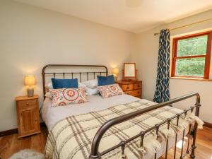 a bedroom with a bed with blue pillows and a window at Oak Apple Cottage in Presteigne