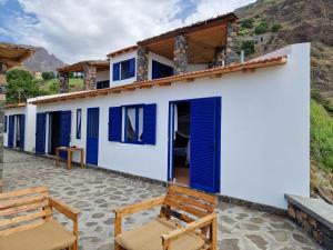 a house with blue doors and two chairs at Casa Saúde in Seladinha