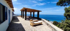 a patio with two benches and a view of the ocean at Casa Saúde in Seladinha