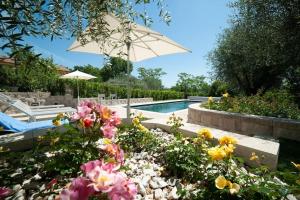 a swimming pool with a garden of flowers and an umbrella at La casa di Giulio e Lina in Fossombrone