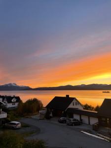 a sunset over a lake with houses and cars at Comfy apartment in Tromsø in Tromsø