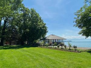 Un césped con un cenador y el agua. en Ferienwohnung Alina- Penthouse Wohnung mit atemberaubendem Blick zum Bodensee, en Kressbronn am Bodensee
