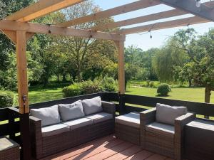 a patio with two couches under a wooden pergola at Tasburgh - Farthings in Norwich