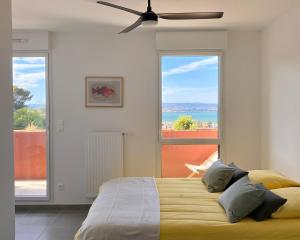 a bedroom with a bed and two large windows at Appartement Vista Mare Sète - vues mer et étang - parking in Sète