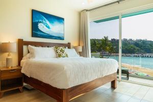 Playa Sur Paradise - Beachfront Living في سانتا كروز هواتولكو: غرفة نوم بها سرير ونافذة كبيرة +28 صورة