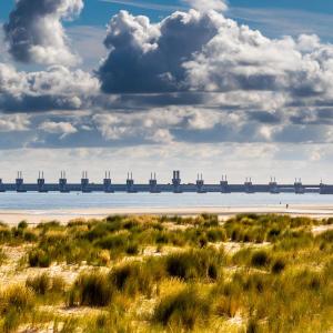 a view of a beach with a bridge in the distance at Bambou Rooms in Vrouwenpolder