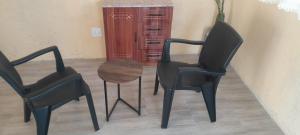 three black chairs and a table in a room at PK house in Mbabat