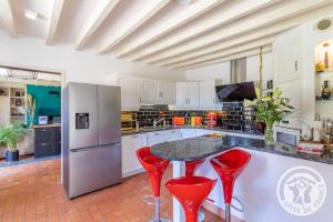 a kitchen with a counter and red stools in it at La coudraie votre maison de vacances en famille in Daumeray