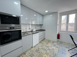 une cuisine avec des armoires blanches, un évier et un micro-ondes dans l'établissement Estoril Escape - Family & Friends Beach Getaway, à Estoril