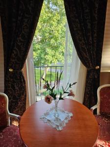a vase with flowers on a table in front of a window at Vila Mažoji apartamentai in Palanga +22 photos