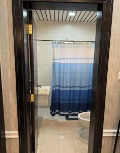 a bathroom with a blue shower curtain and a toilet at قصر الروابي للشقق المخدومة اقتصادي in Riyadh
