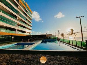 a large building with a swimming pool next to the ocean at Pé na Areia, Piscina Borda Infinita, Vaga de Garagem, Portaria 24 hs in Salvador