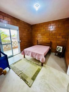 a bedroom with a bed and a brick wall at Casa com Vista do Mar e Montanha in Peruíbe