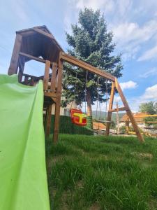 a wooden play structure in the grass with a slide at Мальовица - къща за гости in Dospey Makhla