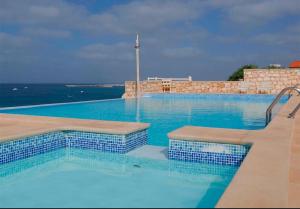 a large swimming pool with blue water at Garoupa Stella Maris Apartamento N10 in Vila do Porto