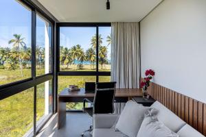 a living room with a couch and a table with a desk at Nossa Casa | Frente Mar, 5 Suítes Exclusivas in Praia do Forte