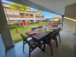 a dining room with a table and chairs and a balcony at Village Térreo Acqua Guarajuba in Guarajuba